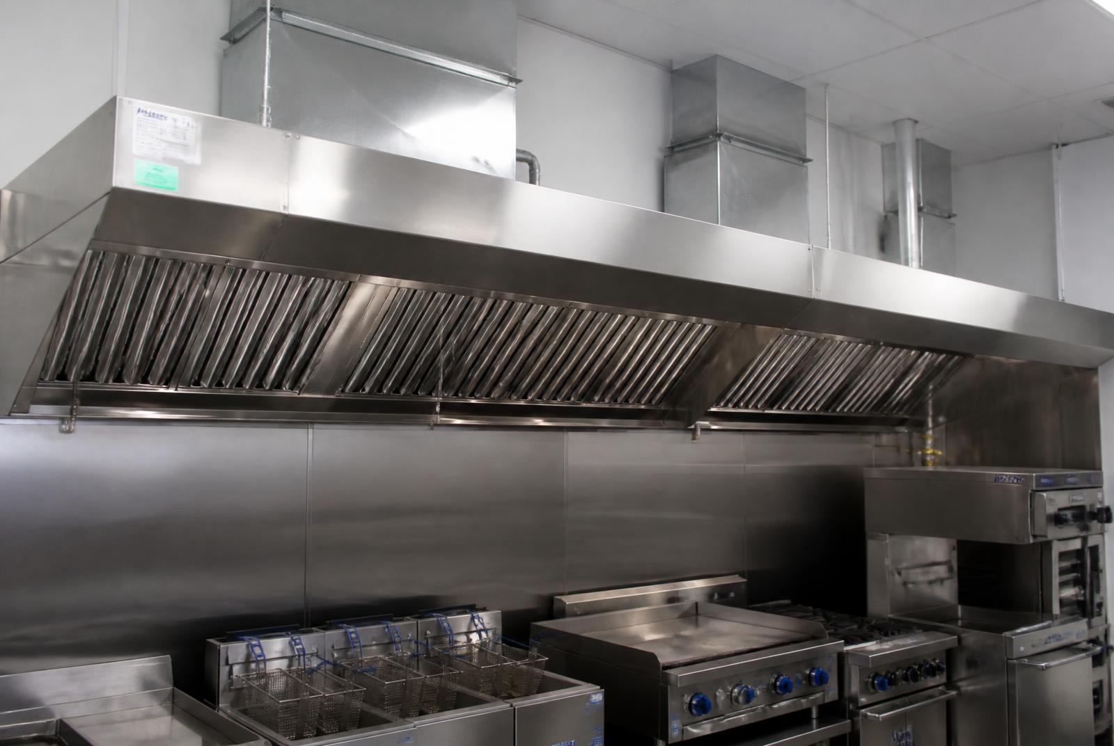 Stainless steel commercial kitchen extract canopy and extract ductwork in a professional kitchen